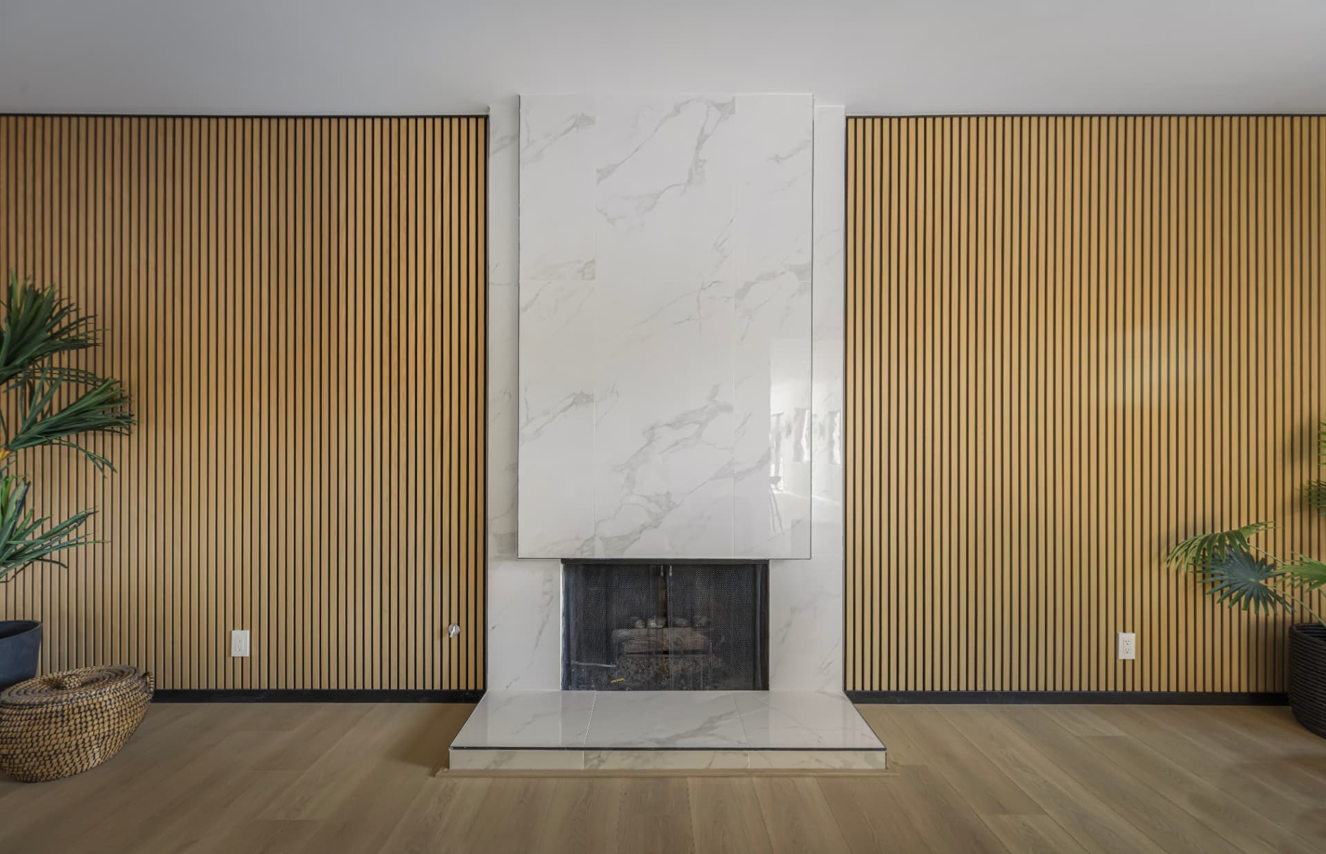 Marble-inspired fireplace framed by floor-to-ceiling vertical wood slat walls
