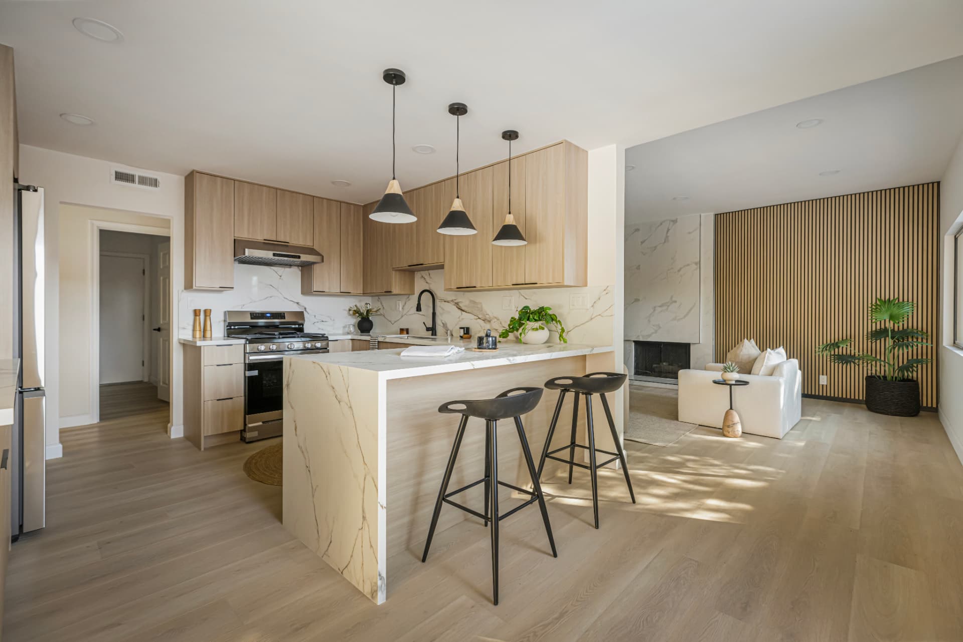 Updated kitchen with light wood cabinetry, stone peninsula and black pendant lighting